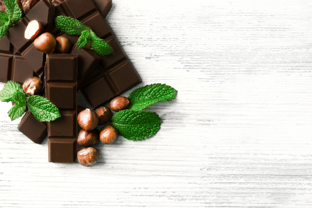 Chocolate pieces with nuts on color wooden backgroundの写真素材