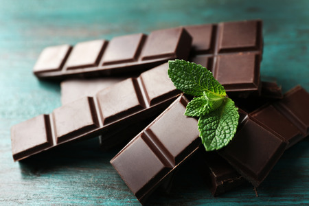 Black chocolate pieces on color wooden backgroundの写真素材