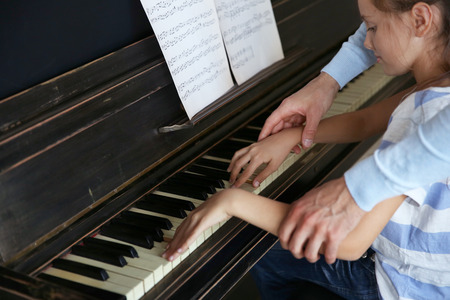 Musician teacher and little girl play piano togetherの写真素材