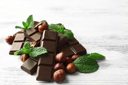 Chocolate pieces with nuts on color wooden backgroundの写真素材