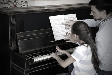 Musician teacher and little girl play piano togetherの写真素材