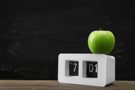 Green apple and clock on blackboard backgroundの写真素材