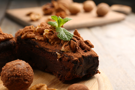 A piece of chocolate cake with walnut and mint on the table, close-upの写真素材