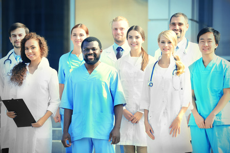 Smiling team of young doctors against hospital entranceの写真素材
