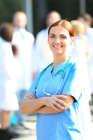 Portrait of woman doctor standing against unfocused group of medicsの写真素材