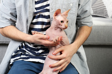 Young man sitting with cat on floor at homeの写真素材