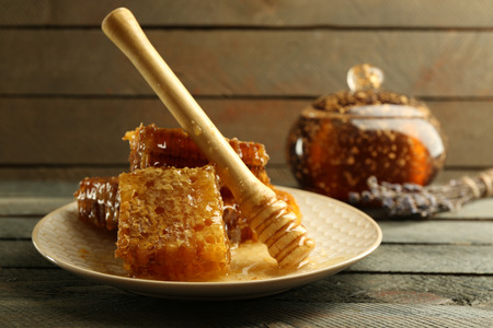 Honeycombs and wooden dipper on plate on wooden backgroundの写真素材