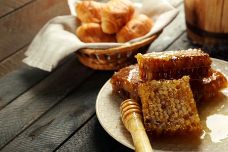 Honeycombs on plate, hot buns in basket on wooden backgroundの写真素材