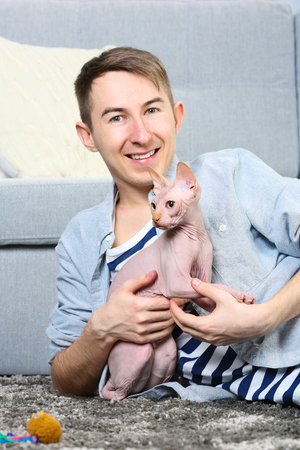 Young handsome man lies with cat on floor at homeの写真素材