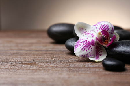 Black pebbles with orchid on wooden tableの写真素材