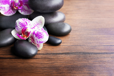 Black pebbles with orchid on wooden backgroundの写真素材