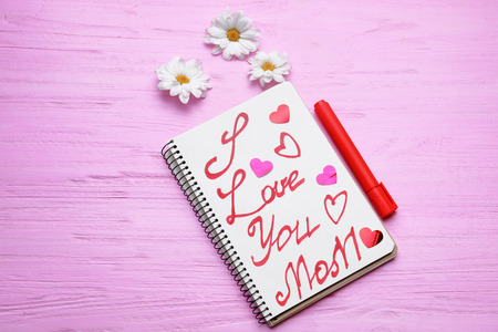 Notebook with text I LOVE YOU MOM on wooden background. Greetings for Mother's Dayの写真素材