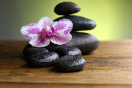 Black pebbles with orchid on wooden tableの写真素材