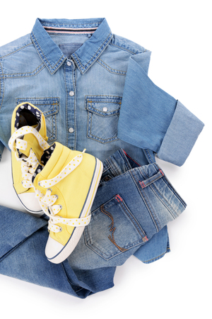 Blue denim shirt and jeans with yellow gym shoes on white backgroundの写真素材