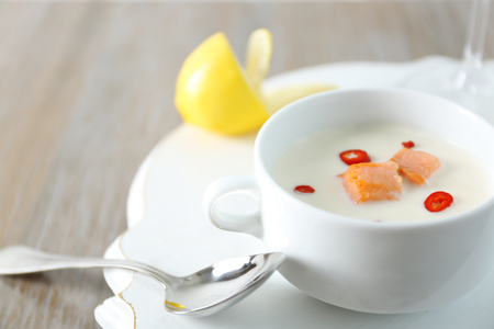 Tasty salmon cream soup, wine and lemon on wooden table, close upの写真素材