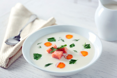 Delicious cream soup with salmon and carrot in white bowlの写真素材