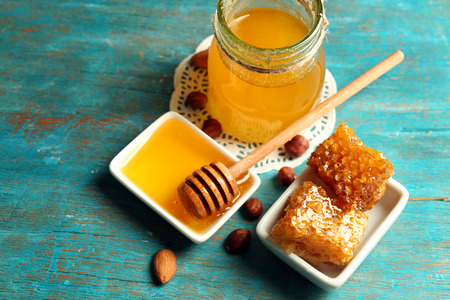 Honeycomb, glass pot with honey and nuts on color wooden backgroundの写真素材