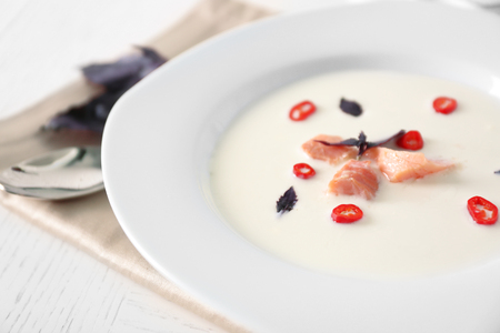 Delicious cream soup with fish and basil on white served table in the restaurantの写真素材