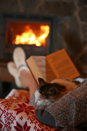 Woman resting with book near fireplaceの写真素材