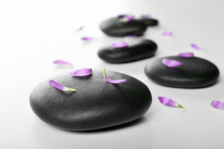 Hot spa stones with flower petals, isolated on whiteの写真素材