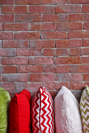 Multicoloured pillows on a brick wall backgroundの写真素材