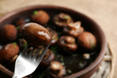 Baked champignons mushrooms with butter, parsley and roasted garlic in brown bowlの写真素材