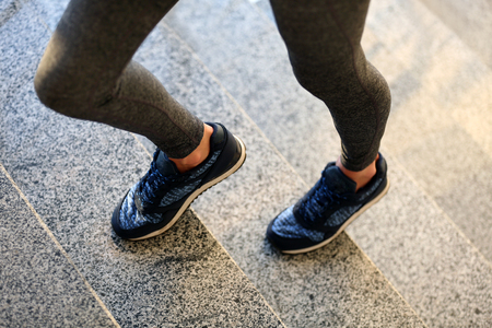 Sports woman legs in sneakers on stairsの写真素材