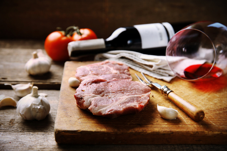 Marbled beef steak with bottle of wine and spices on wooden backgroundの写真素材