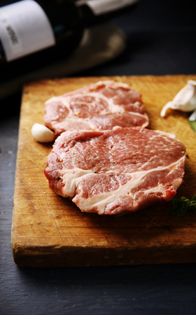 Marbled beef steak with bottle of wine and spices on wooden backgroundの写真素材