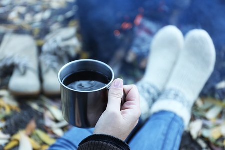 Woman sitting beside the fire with a cup of coffeeの写真素材