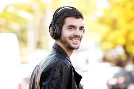 Young man listening to music and walking along the streetの写真素材