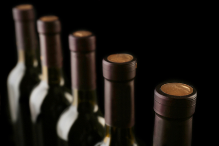 Wine bottles in a row on black  background, close upの写真素材