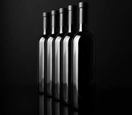 Wine bottles in a row on black  background, close upの写真素材