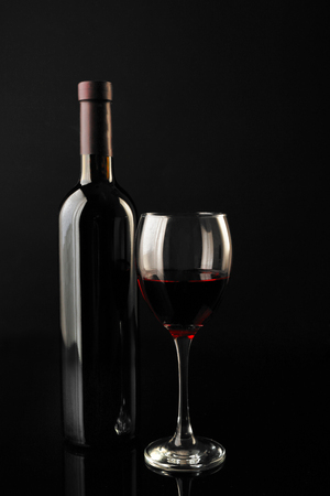 Red wine glass and bottle on black background, close upの写真素材