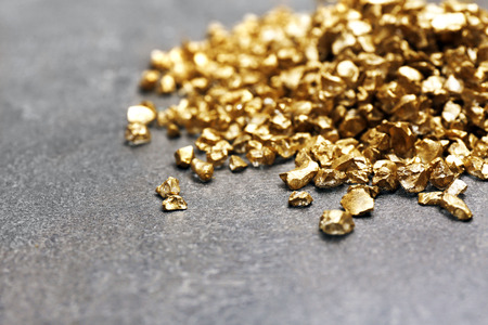 A pile of Gold nugget grains, on cement background