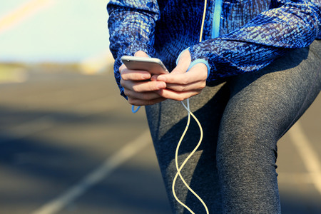 Woman in sports clothes and sneakers with cellphone and bottle