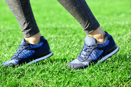 Sports woman legs in sneakers on grass outdoorの写真素材