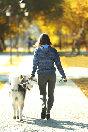 Happy young woman jogging with her dog in parkの写真素材
