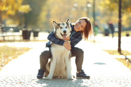 Happy young woman walking with her dog in parkの写真素材