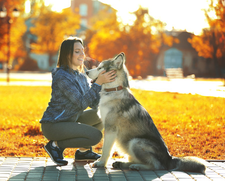 Happy young woman walking with her dog in parkの写真素材