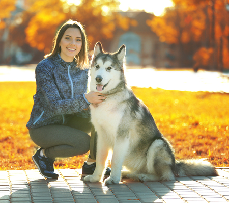Happy young woman walking with her dog in parkの写真素材
