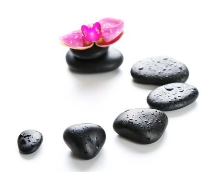 Black spa stones and orchids isolated on whiteの写真素材