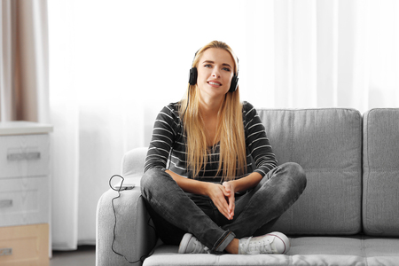 Young woman sitting and listening to music in a roomの写真素材