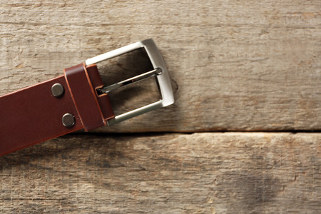 Leather belt with buckle on wooden background