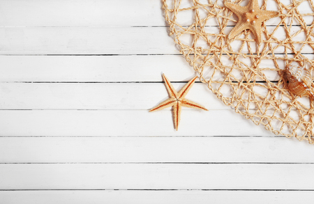 Seashells and fishing net on wooden backgroundの写真素材