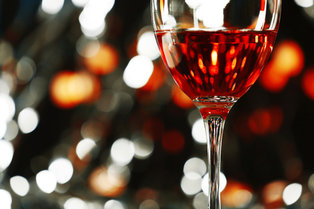A glass of pink wine on blurred lighted backgroundの写真素材