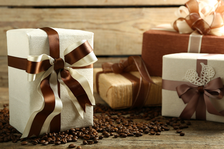 Beautiful gifts with bows and coffee grains on wooden backgroundの写真素材