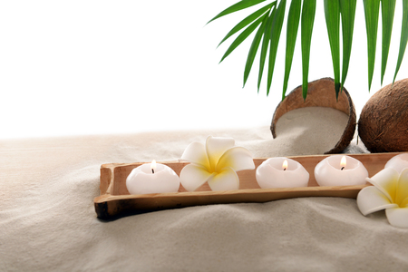 Coconut with candles and plumeria on sand, isolated on whiteの写真素材