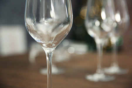 Empty wine glasses on wooden table against blurred backgroundの写真素材