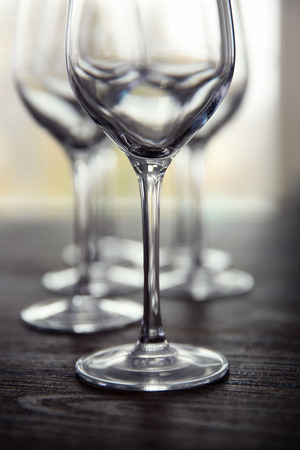 Empty wine glasses on wooden table against blurred backgroundの写真素材